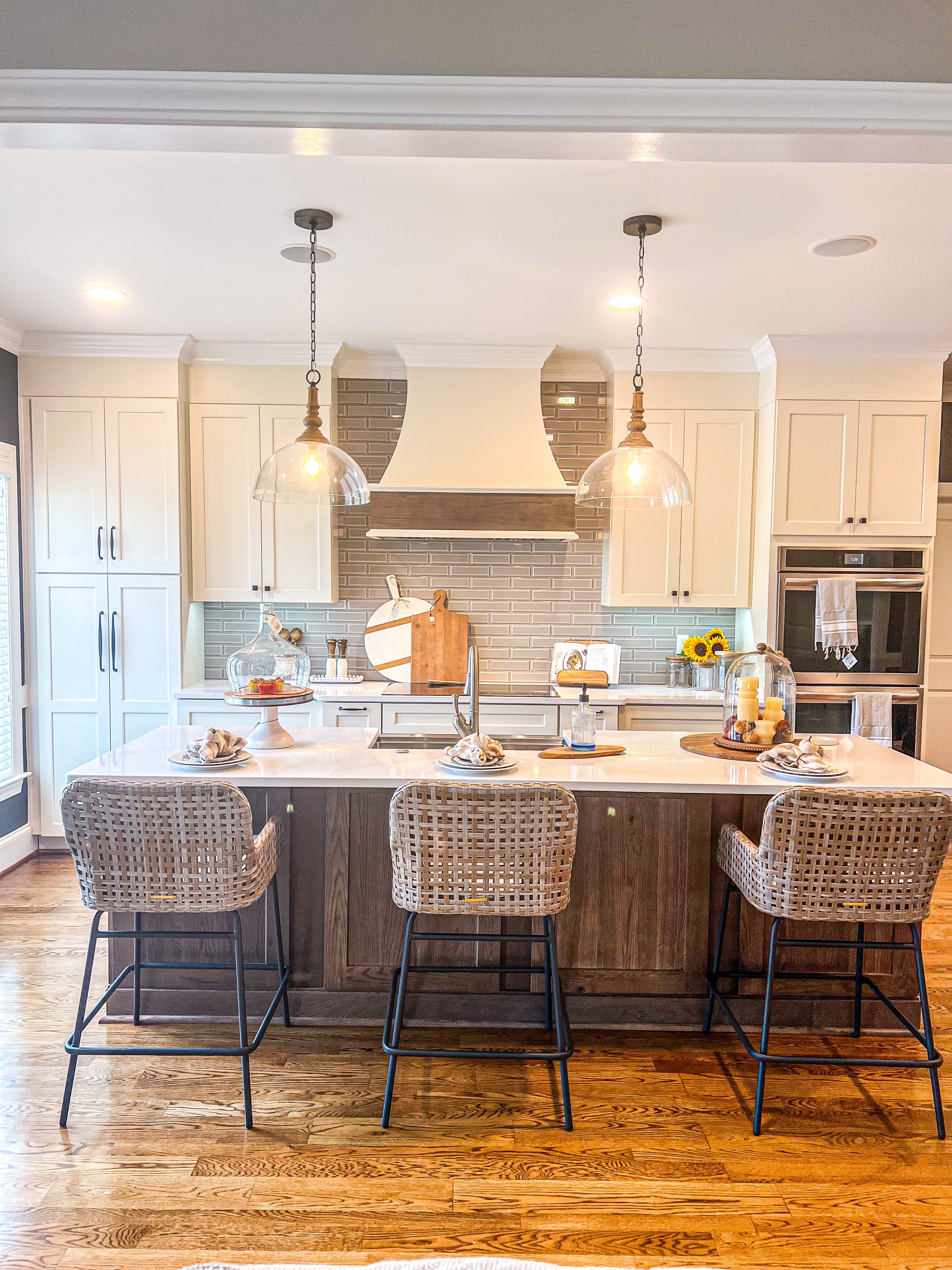 renovated kitchen with rattan bar chairs, modern lighting pendants, white cabinets
