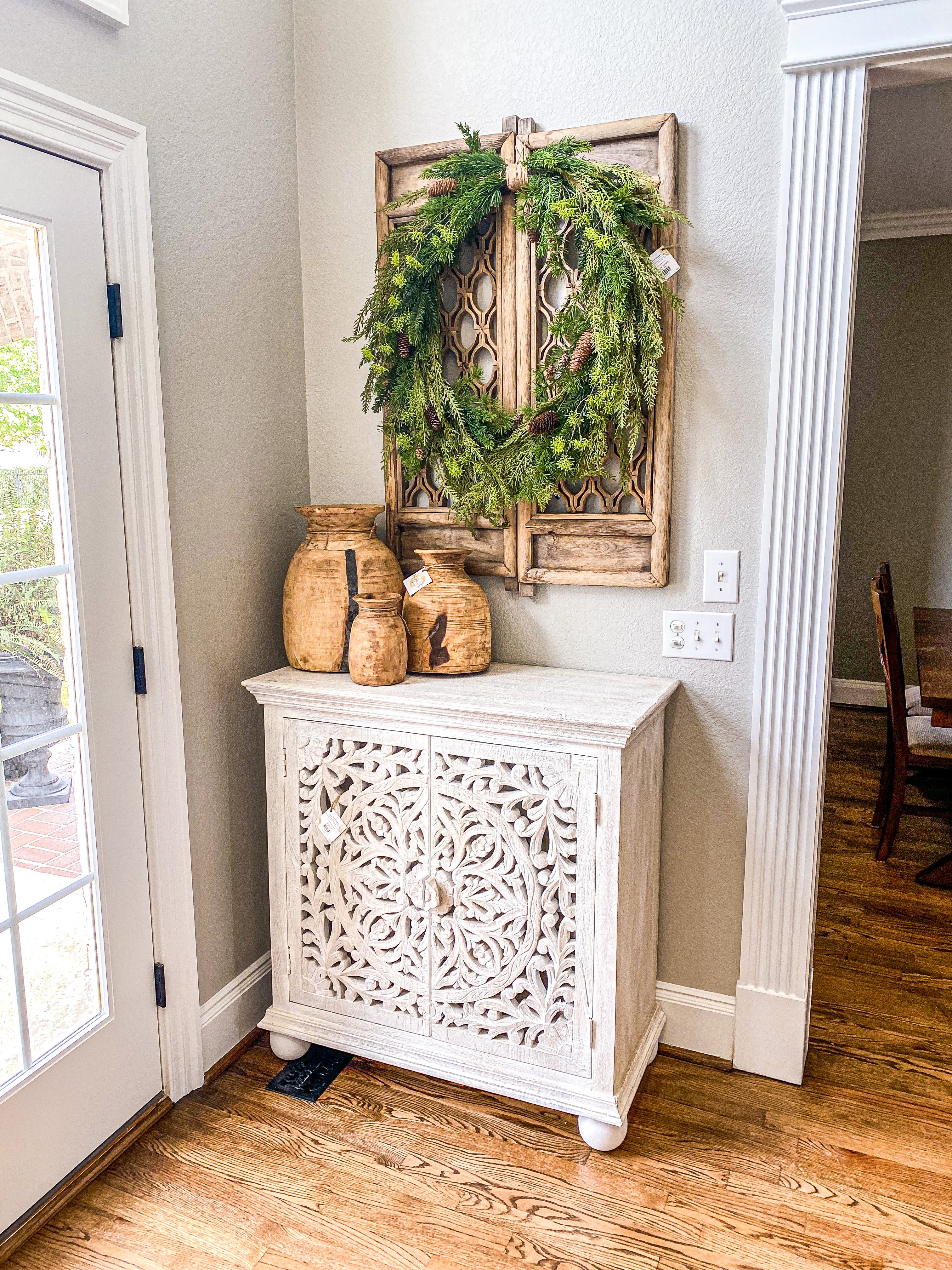 distressed cabinet with three jars and big foliage wreath