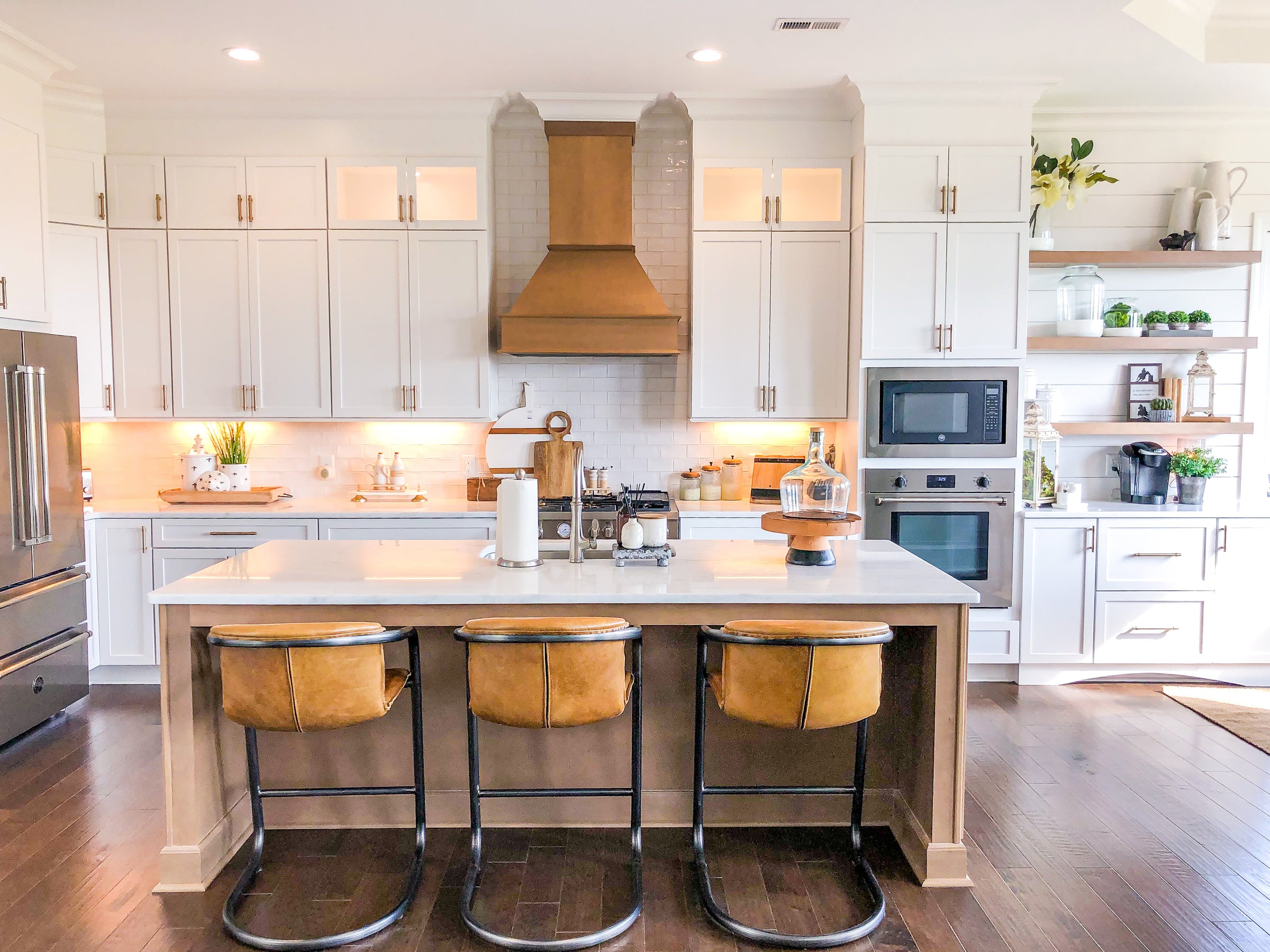 White kitchen with island and three leather barstools